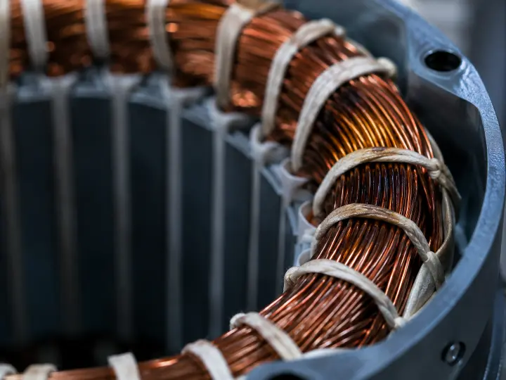 Close-up of a compressor motor's copper windings showing early heat discoloration, a warning sign of gradual winding failure.