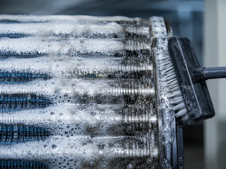 Evaporator coil being treated with foaming coil cleaner and a fin brush, the level of cleaning a heavily fouled coil needs to restore heat transfer.